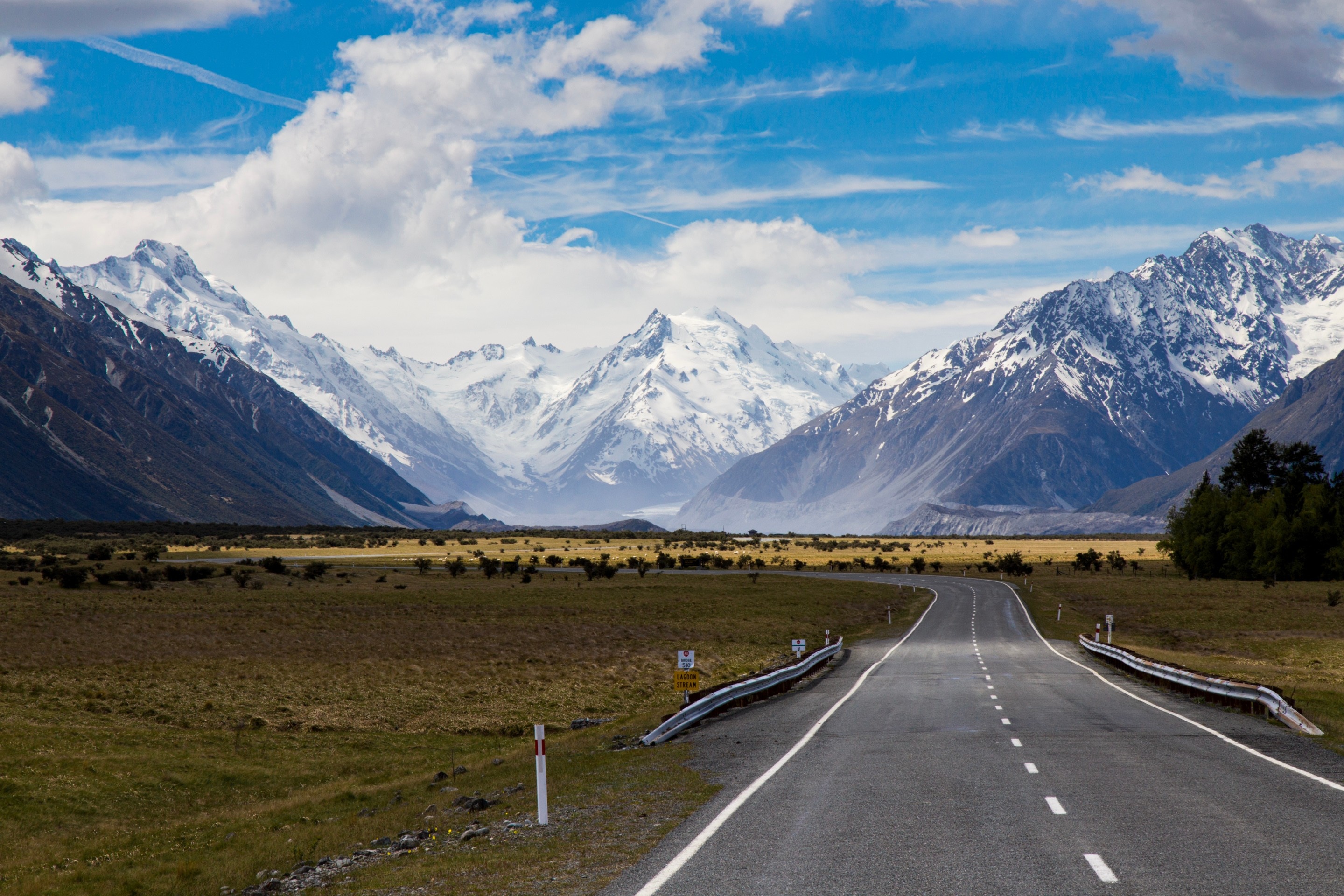An epic shot of the Southern Alps on the South Island of New Zealand. The empty road leads the eye into the disance, where the mountains rise up majestically.