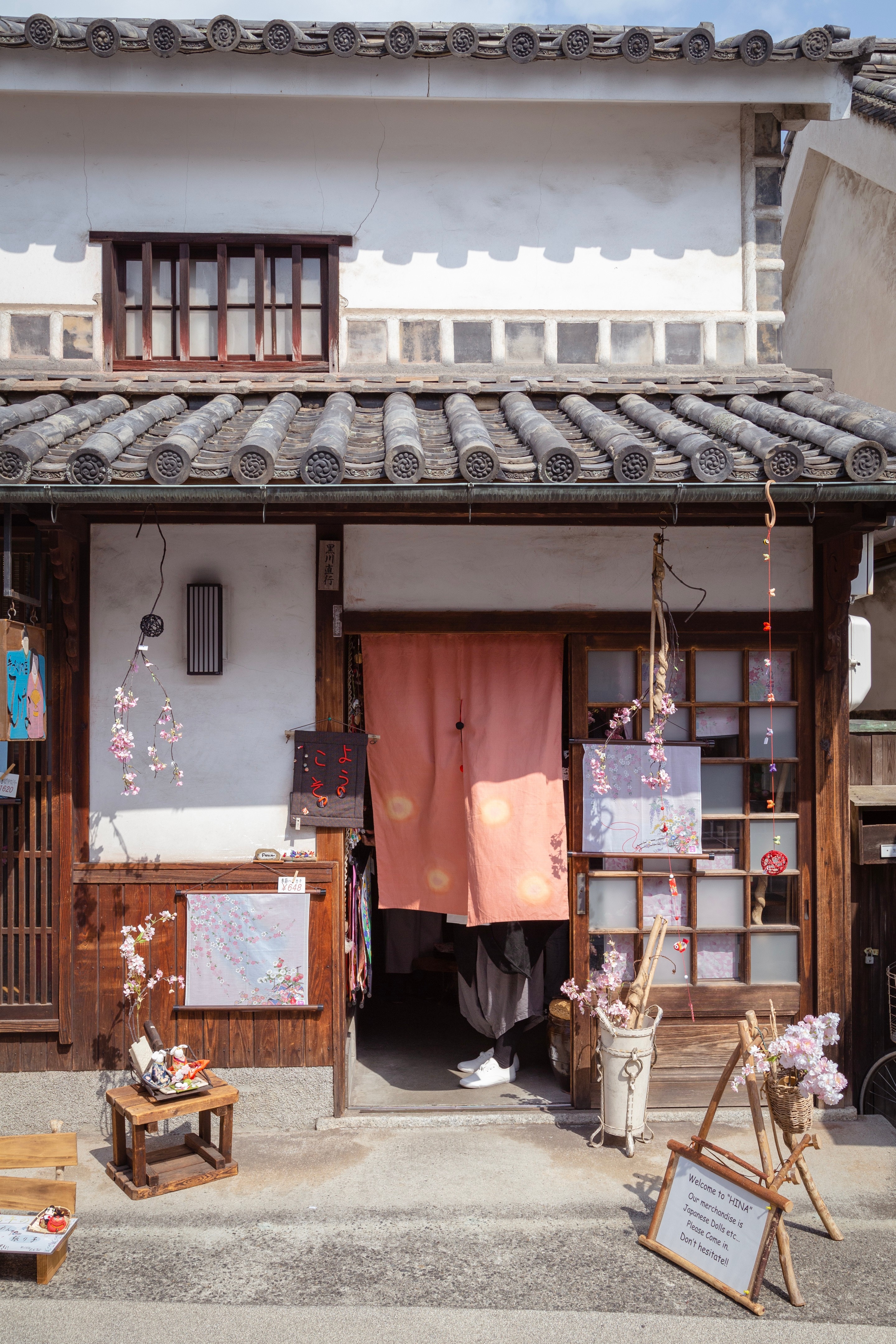 A traditional Japanese curiosity shop decorated in colourful displays of pink flowers — Kurashiki Town, Okayama Prefecture, Japan