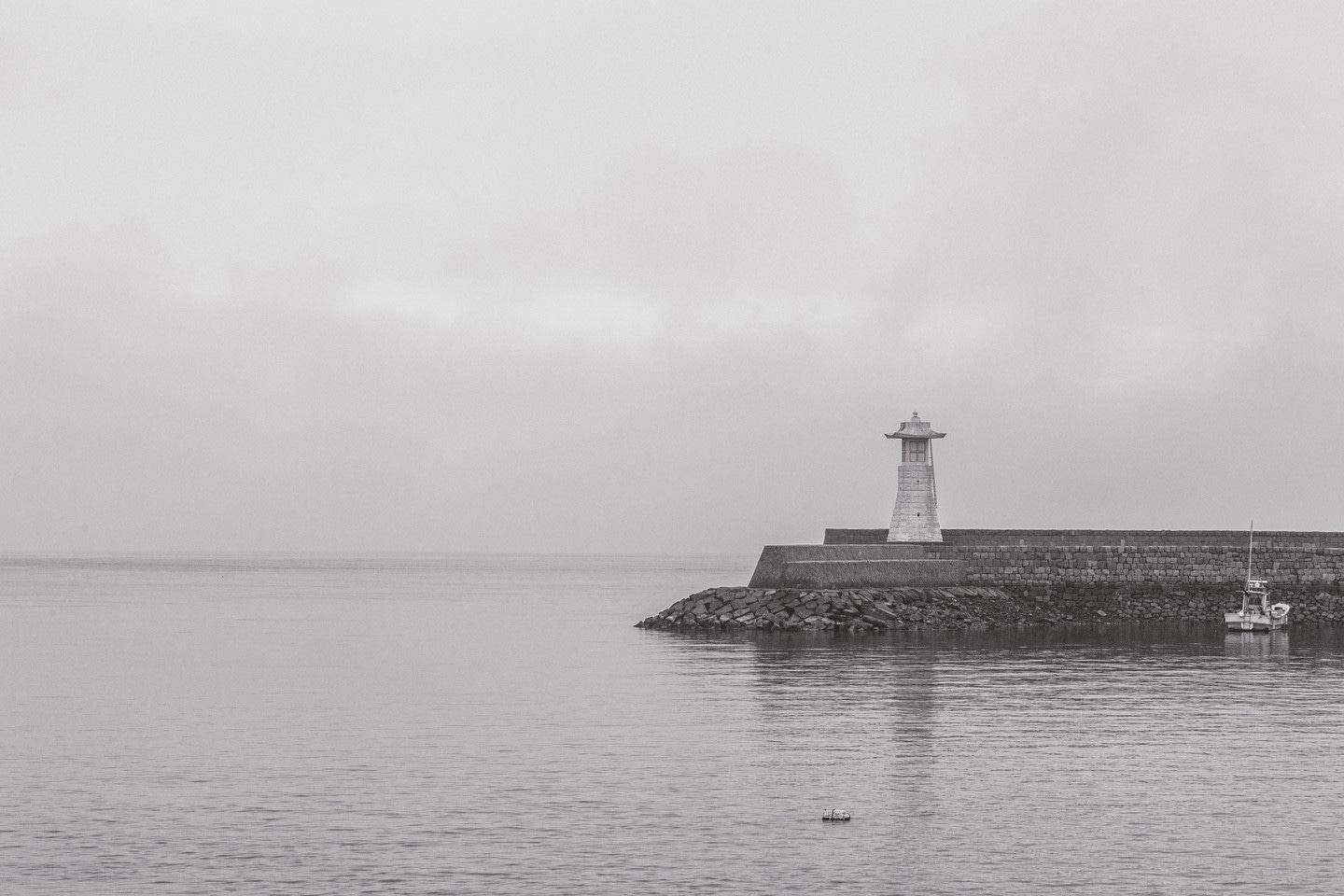 A stone lighthouse at the end of stone harbour jetty in black and white — Mitarai village, Osaki Shimojima Island, Geiyo Region.