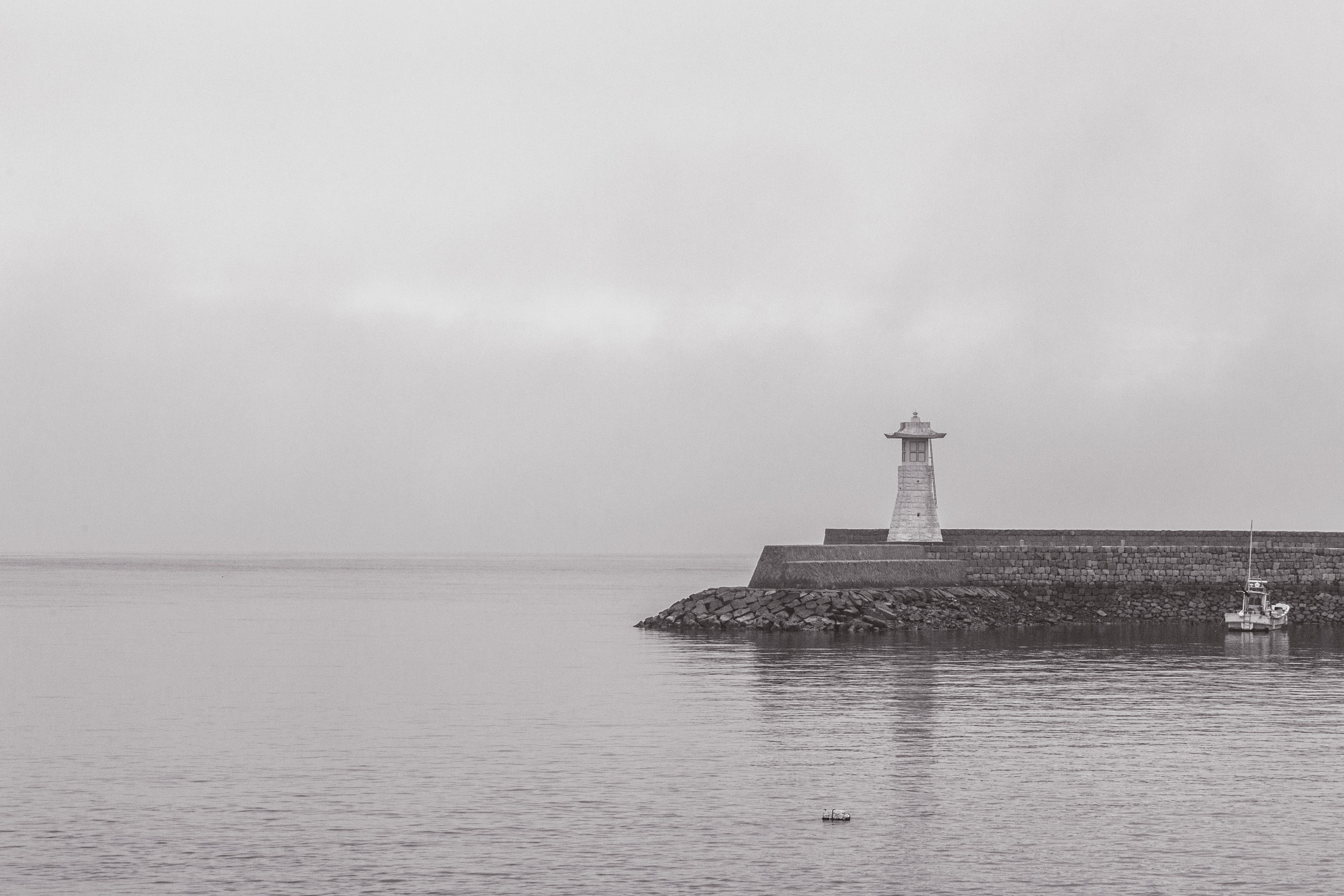 A stone lighthouse at the end of stone harbour jetty in black and white — Mitarai village, Osaki Shimojima Island, Geiyo Region.