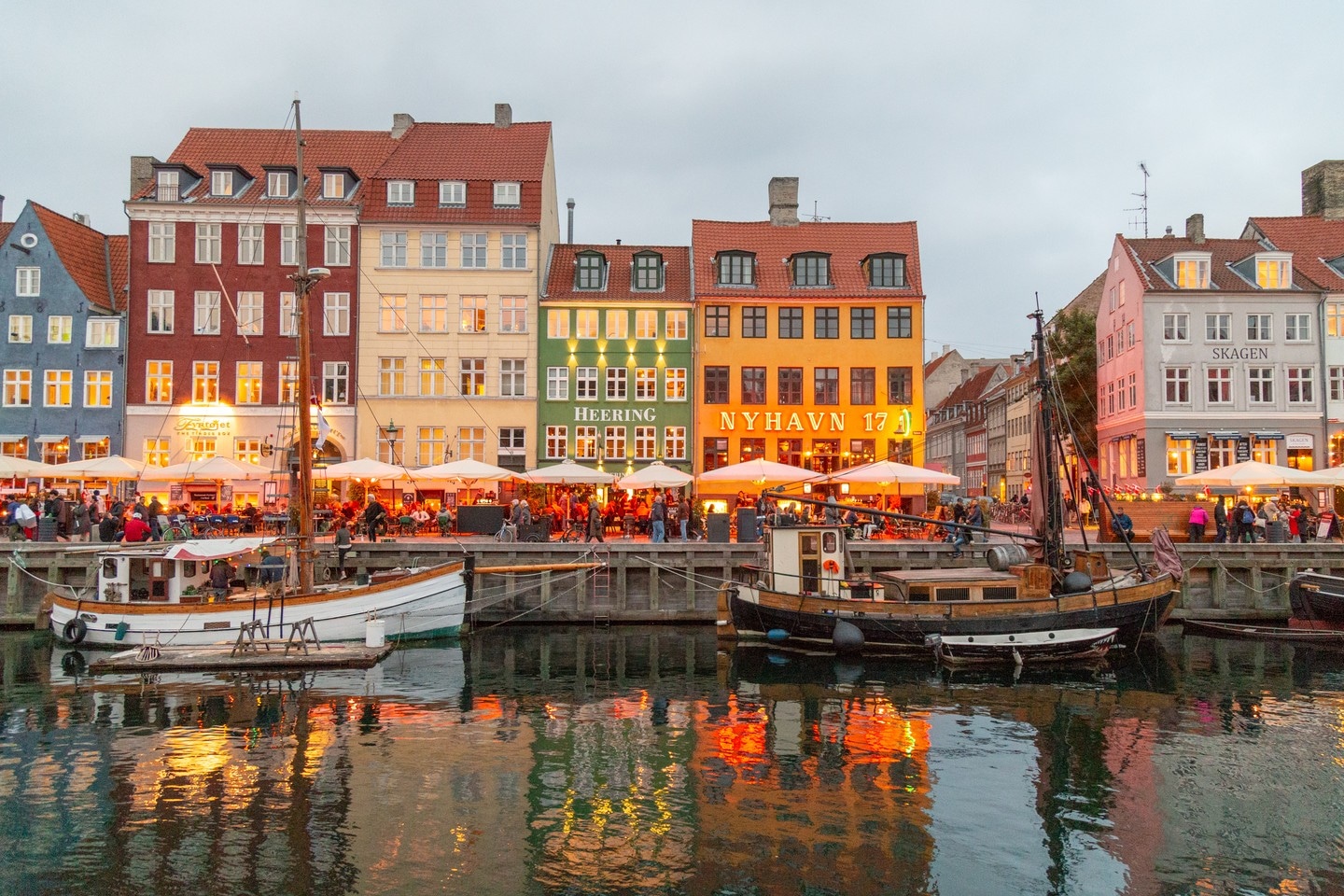 The warm evening colours, lights and activity taken from across the water at Nyhavn Harbour in Copenhagen, Denmark