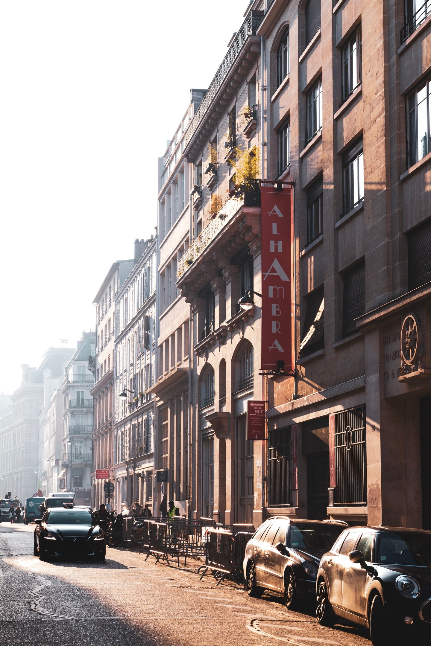 An early morning scene taken in central Paris. The morning sun casts soft shadows down a grand street lined with beautiful old buildings. A black car is seen travelling toward the camera adding counterbalancing interest and movement — Paris, France.