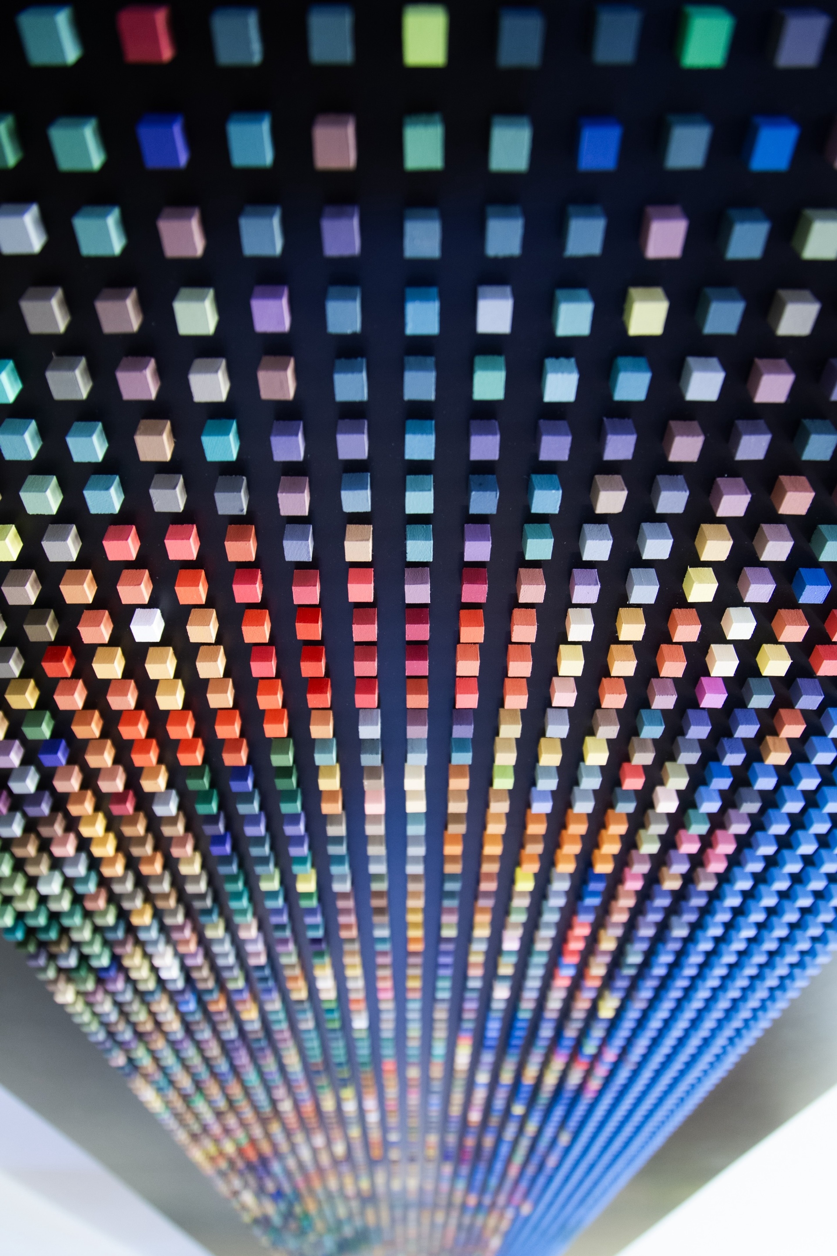 Small coloured cubes act as 'pixels' on a black background. Each pixel a point of light building a picture of the Tokyo cityscape at night. The perpective of the shot is strong. Tokyo, Japan.