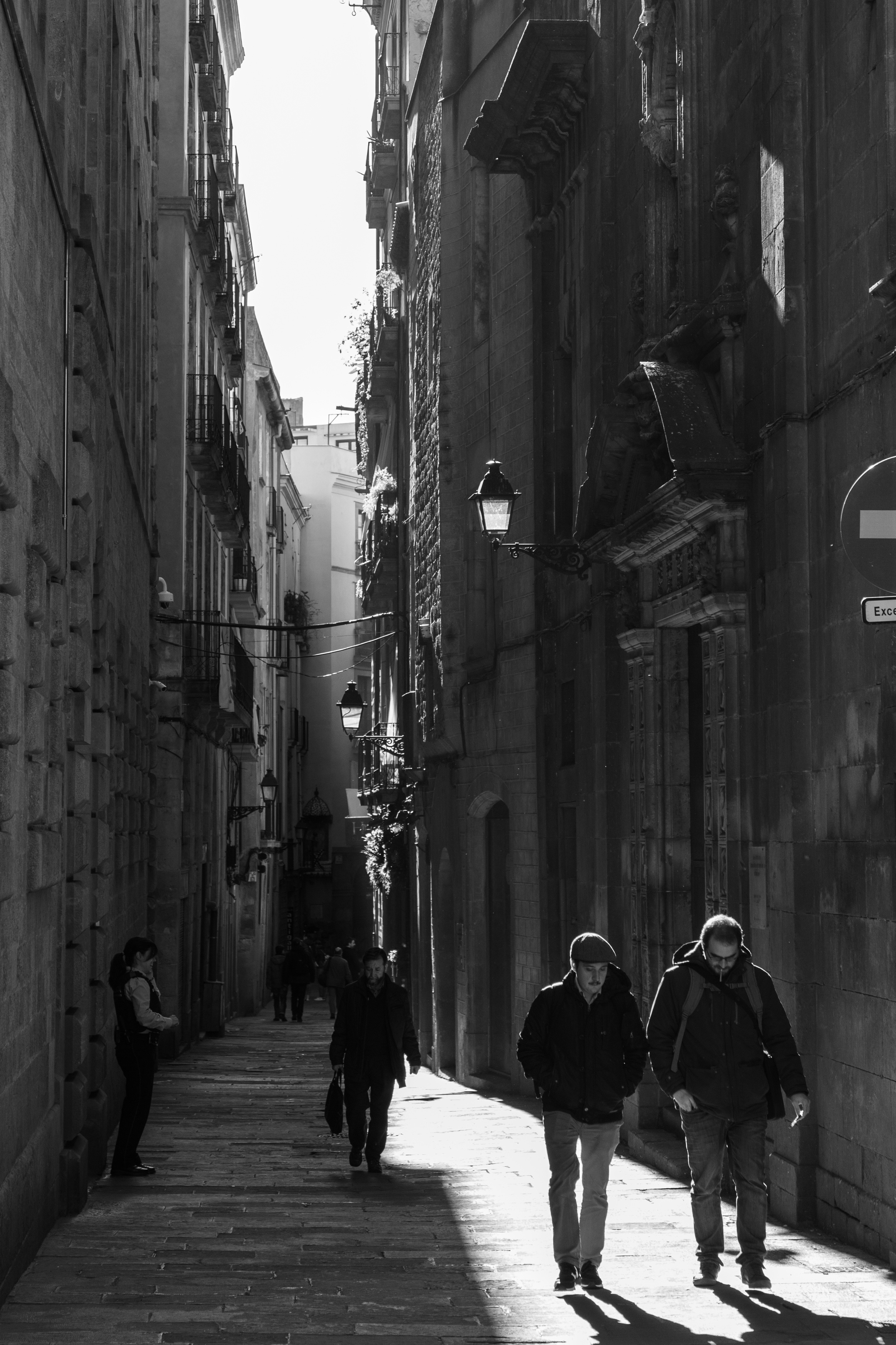 Couple of friends walk a street illuminated by the sun in Barcelona