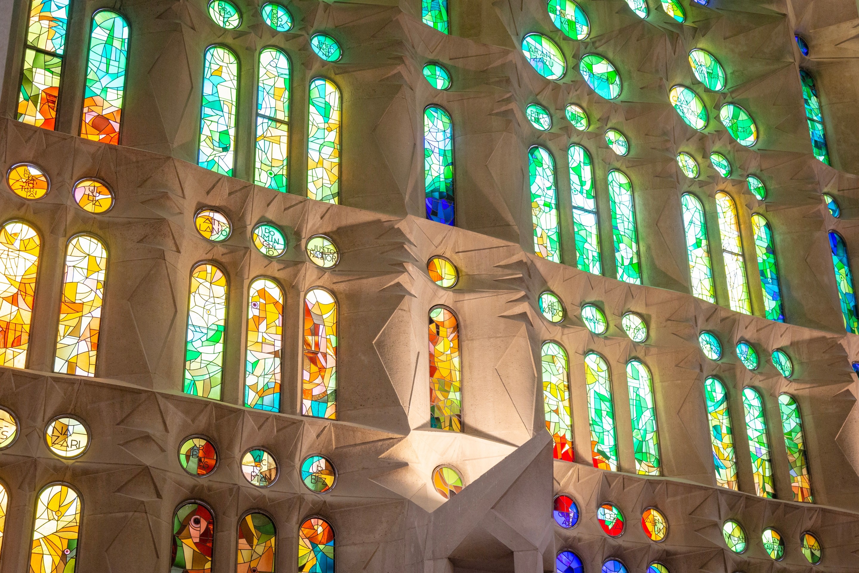Beautiful colourful light streaming through the stained glass windows and illuminating the stone walls. La Sagrada Familia.