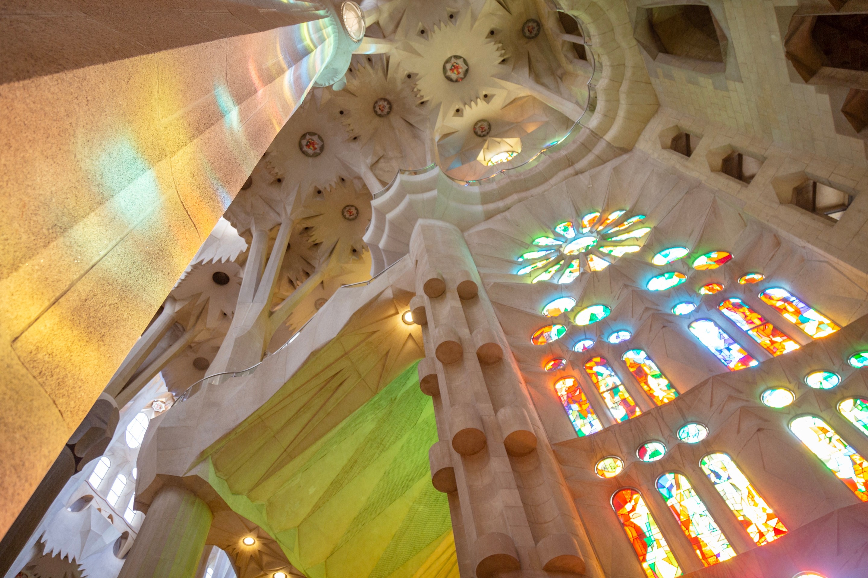 Beautiful colourful light streaming through the stained glass windows and illuminating the stone walls. La Sagrada Familia.
