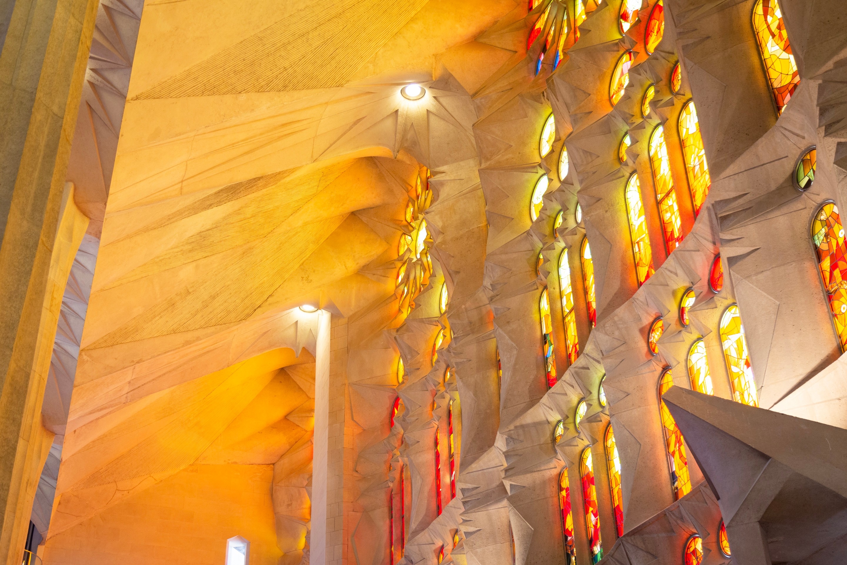 Beautiful colourful light streaming through the stained glass windows and illuminating the stone walls. La Sagrada Familia.