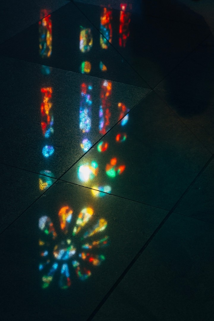 Colourful stained glass reflected in the dark marble floor. La Sagrada Familia.