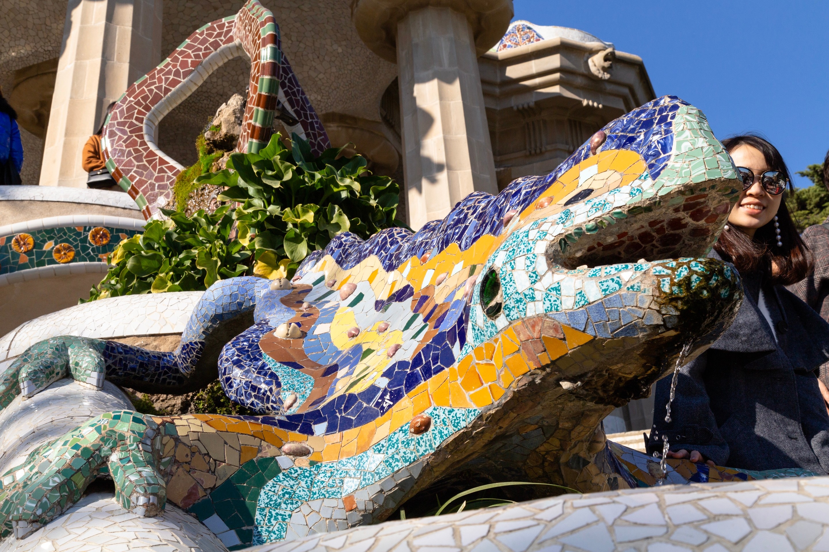 Intricate mosaic tiled large chameleon sculpture above small fountain at Parc Guell, Barcelona.