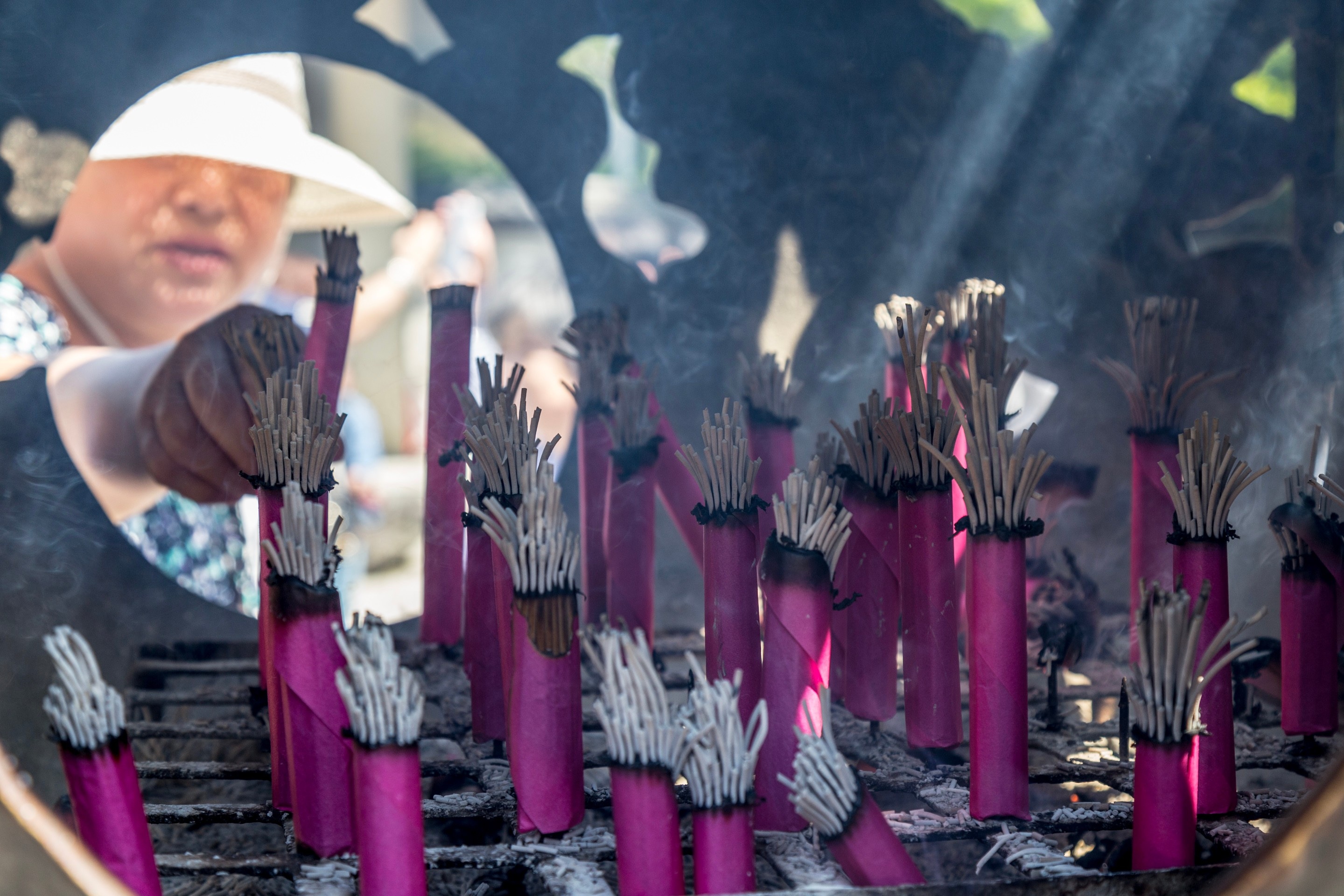 A woman can be seen placing incense into a ceremonial bronze burner in front of the Daibutsu (Giant Buddha) — Kotoku-in Temple, Kamakura, Japan