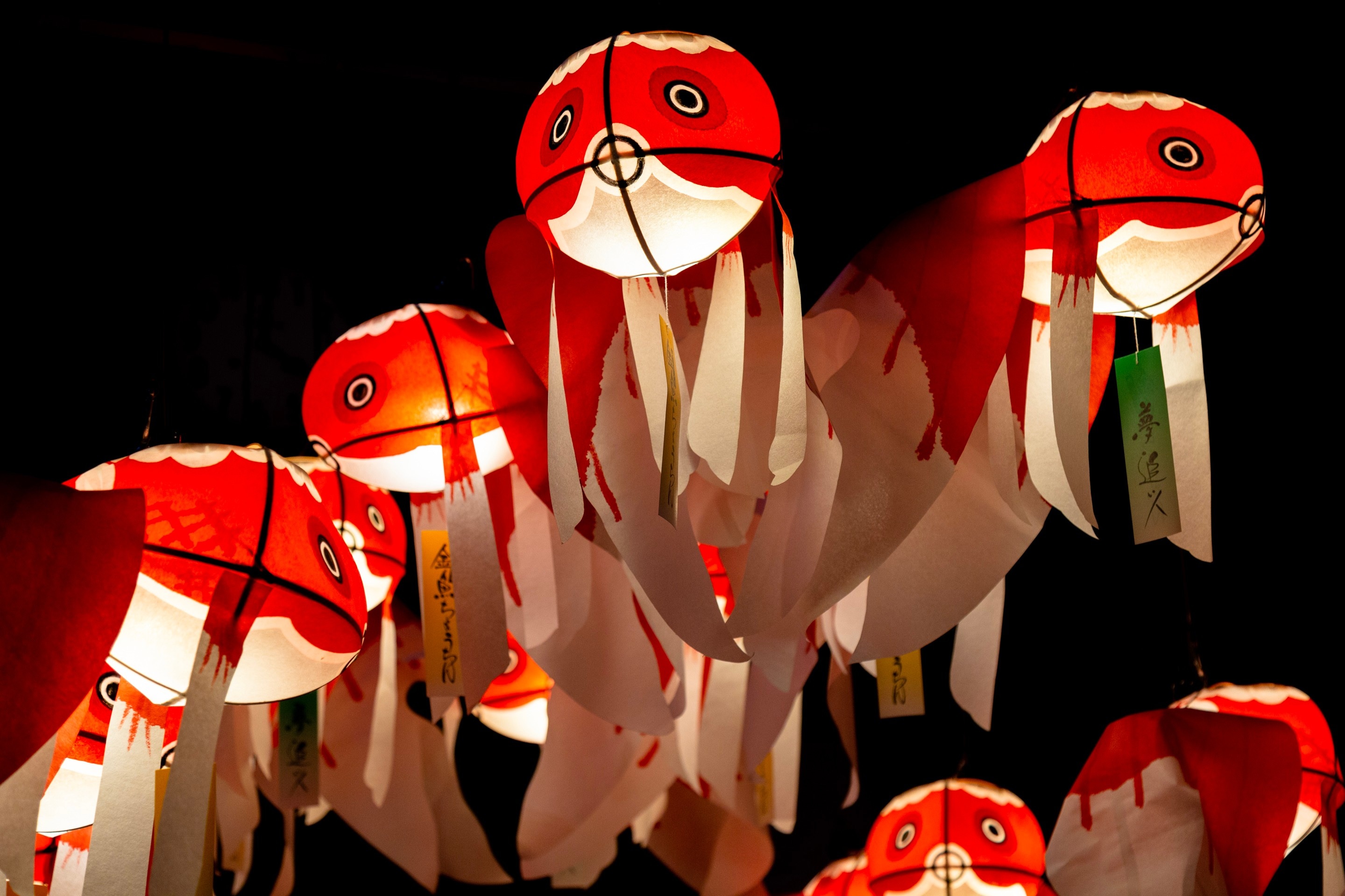Half a dozen illuminated paper goldfish lantern suspended in the air against a black background — Yanai, Yamaguchi Prefecture, Japan