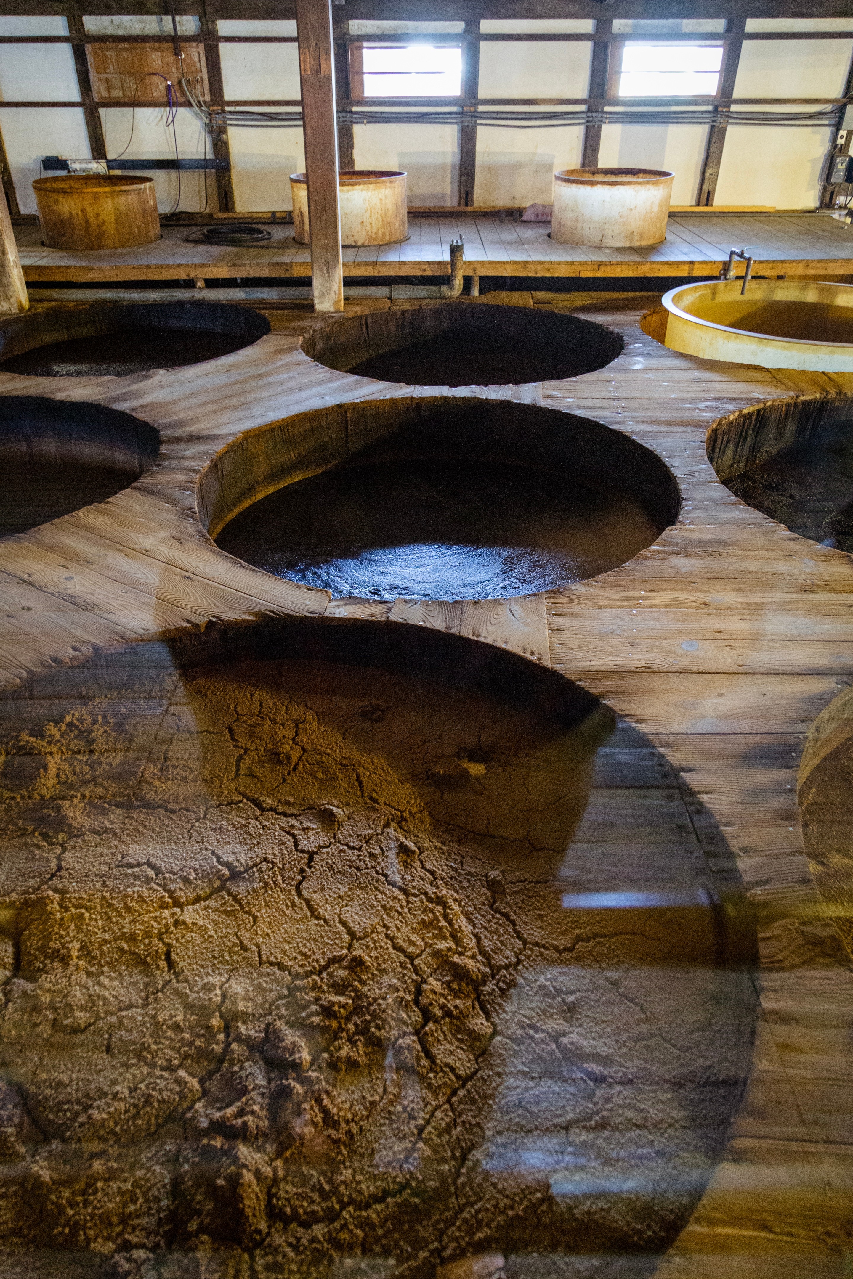 Large circular wooden vats containing fermenting soy sauce Kanro Joyu Soy Sauce Museum — Yanai, Yamaguchi Prefecture, Japan