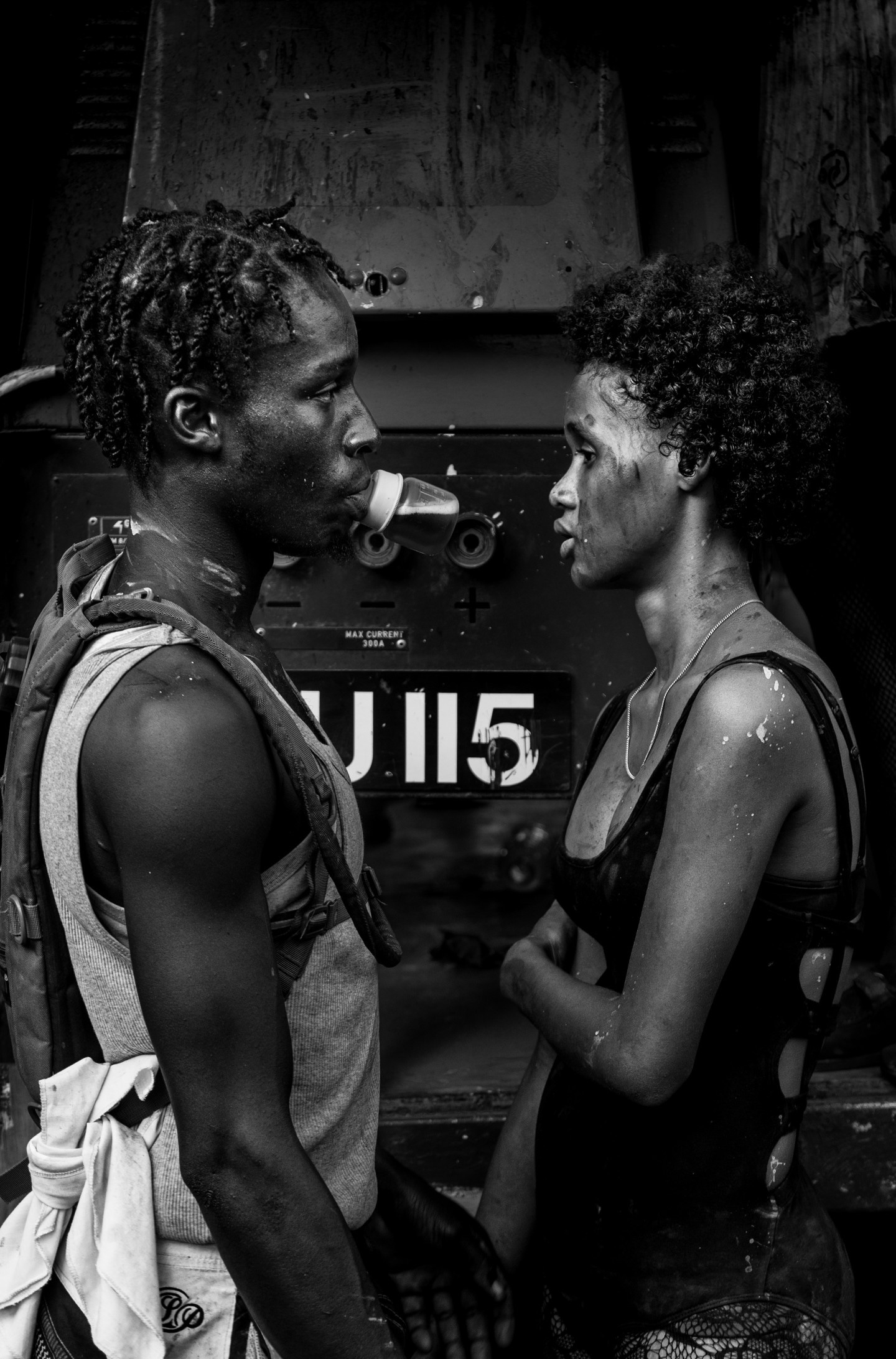 Black and white photo of exhausted party revelers covered in vibrant paints, seen facing to each other clearly tired from the night's proceedings. Taken at Vincy Mas, the annual carnival— Kingstown, Saint Vincent and the Grenadines