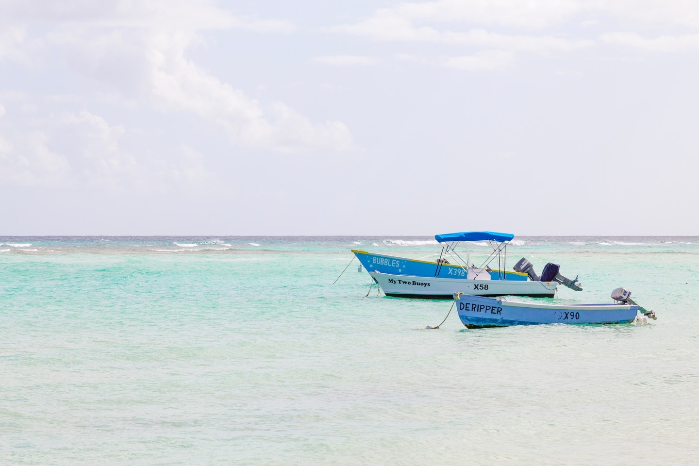 Three small anchored boats bob in the tranquil aquamarine waters of the Caribbean Sea — Barbados