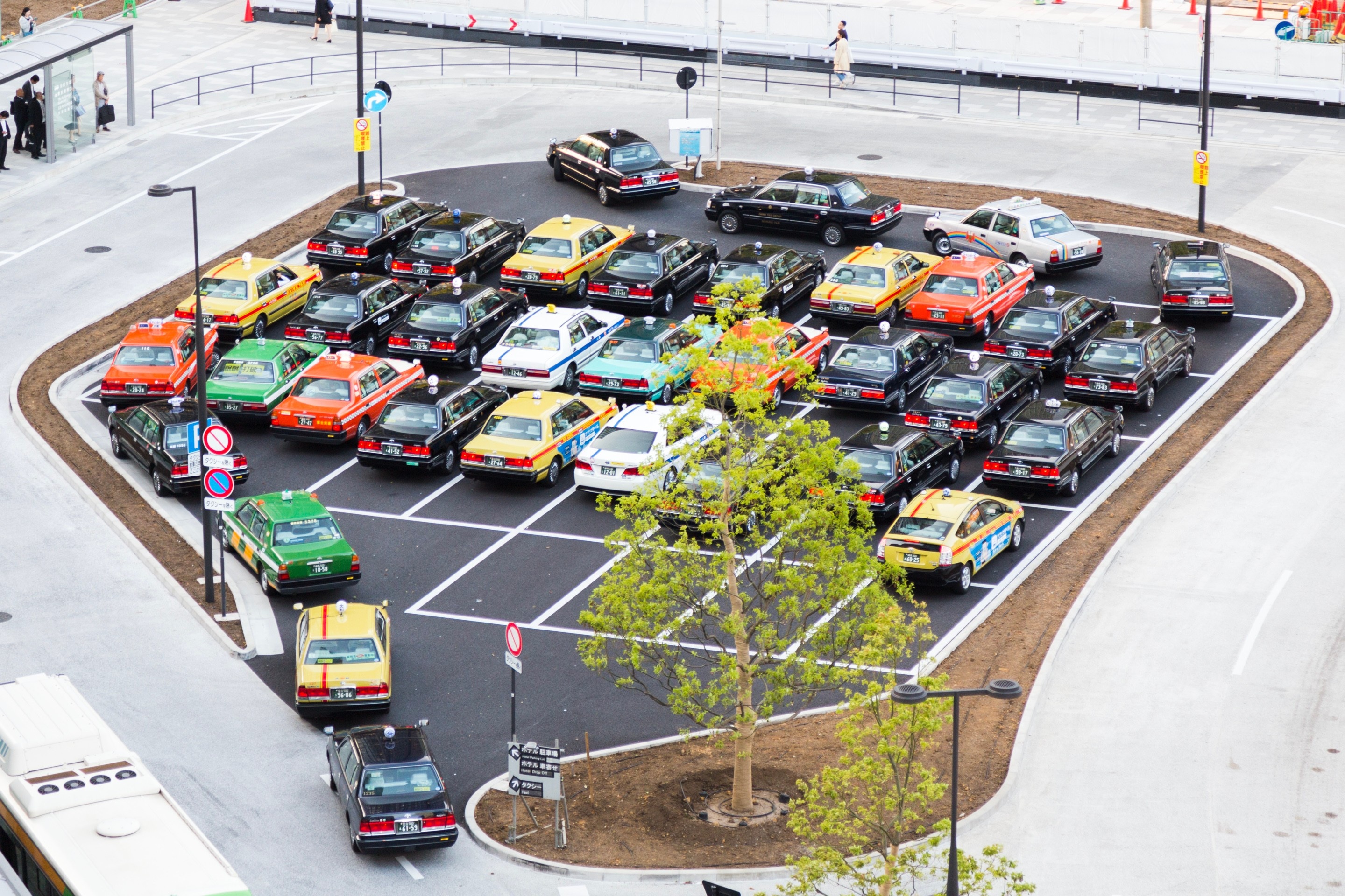 An intriguing taxi rank outside Tokyo Central Station. Pristine taxis patiently queue in grid formation whilst awaiting passengers — Tokyo, Japan