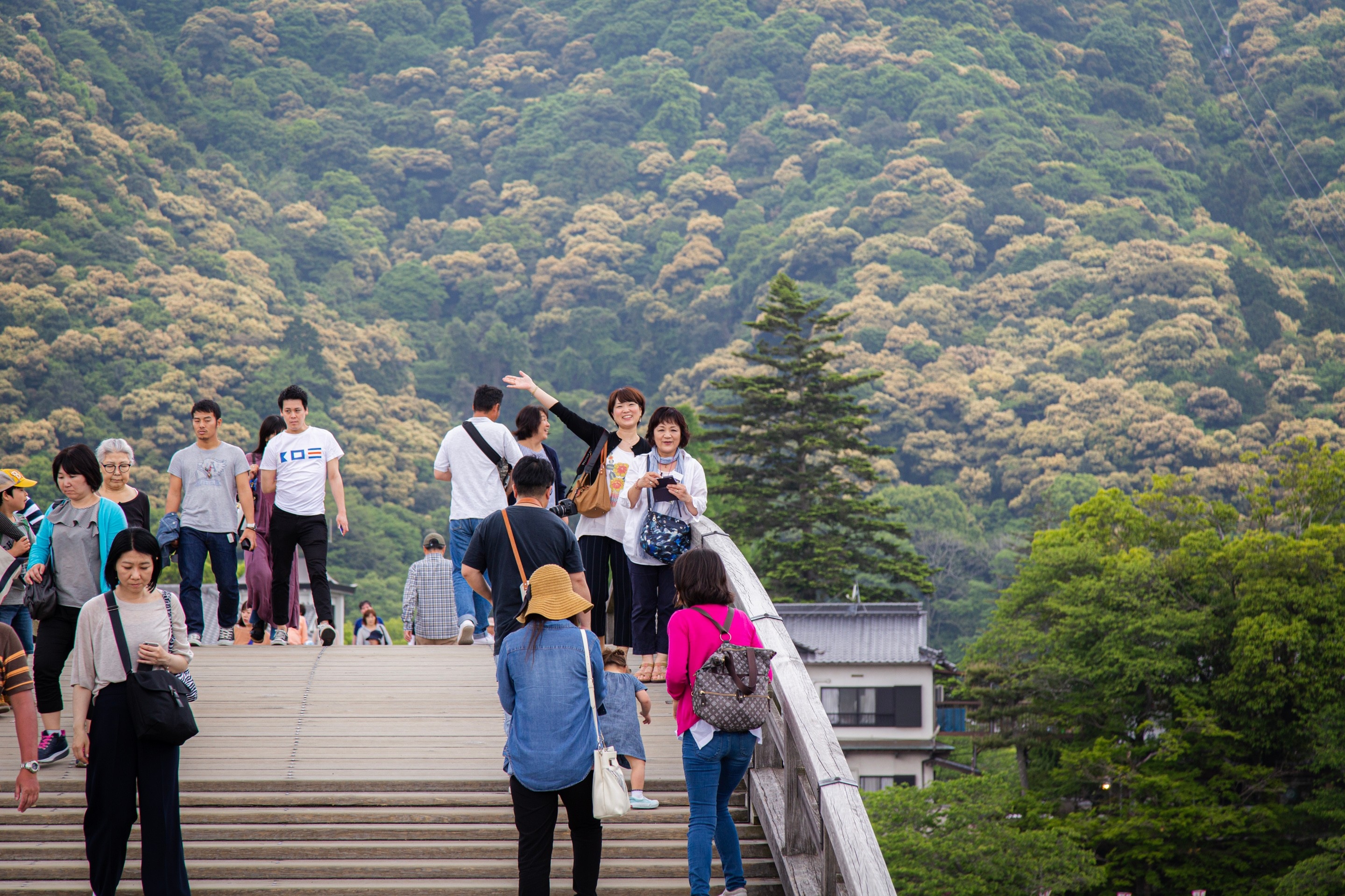People waving towards the photographer on the Kintaikyo Bridge. Iwakuni City, Yamaguchi Prefecture.