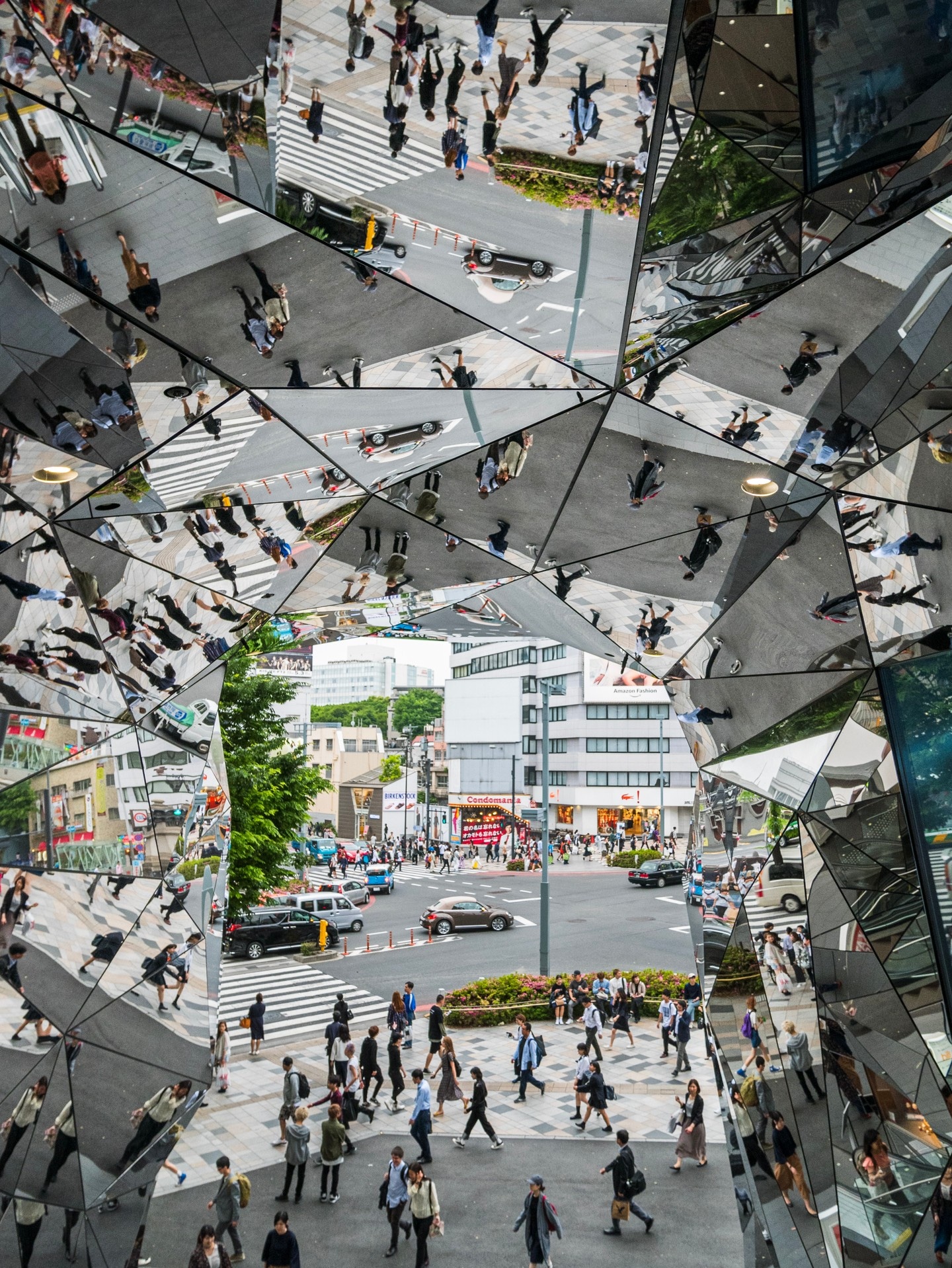 Looking out through the entrance to Tokyu Plaza, which is short tunnel covered in mirrored polygons — Harajuka, Japan.