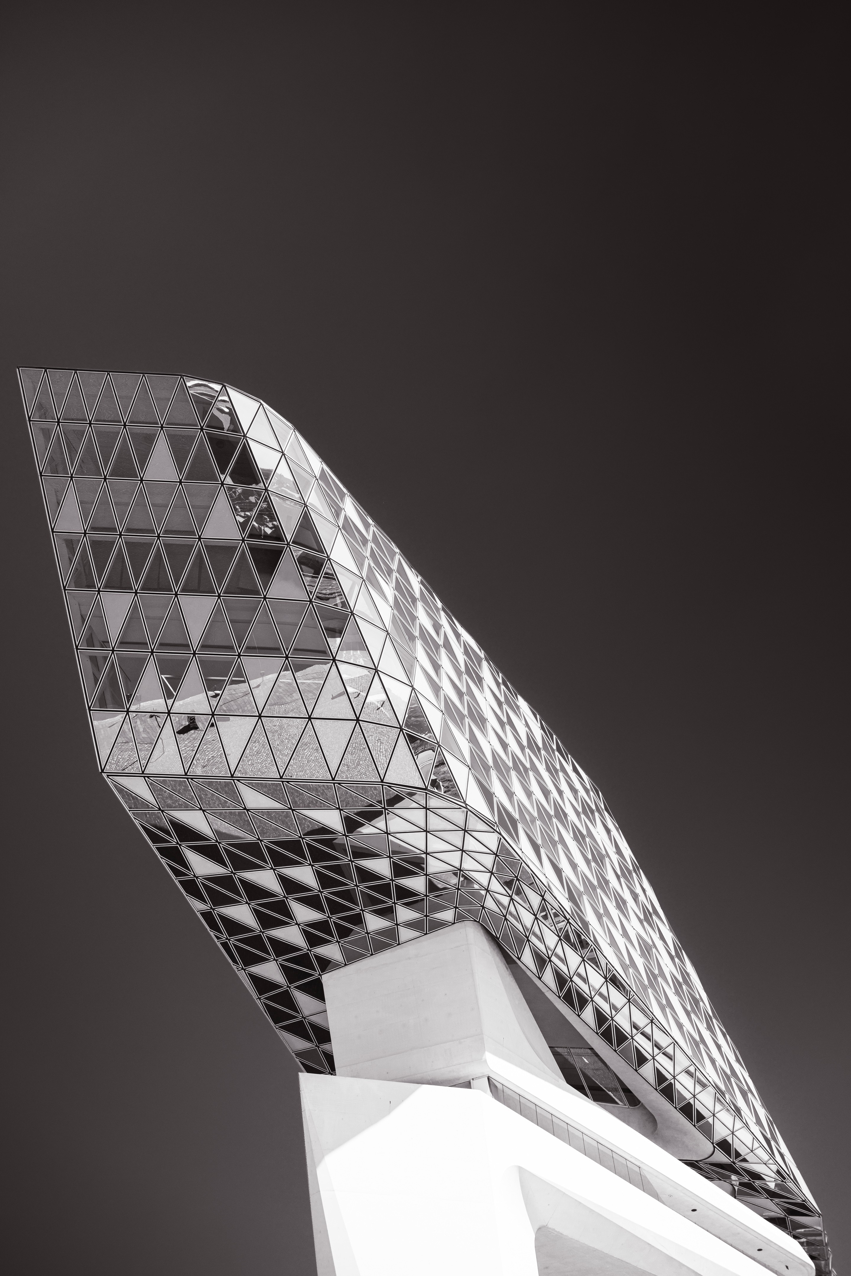 Monochrome high contrast perspective of the glass extension and the top of the concrete support column on the Port House by Zaha Hadid — Antwerp, Belgium