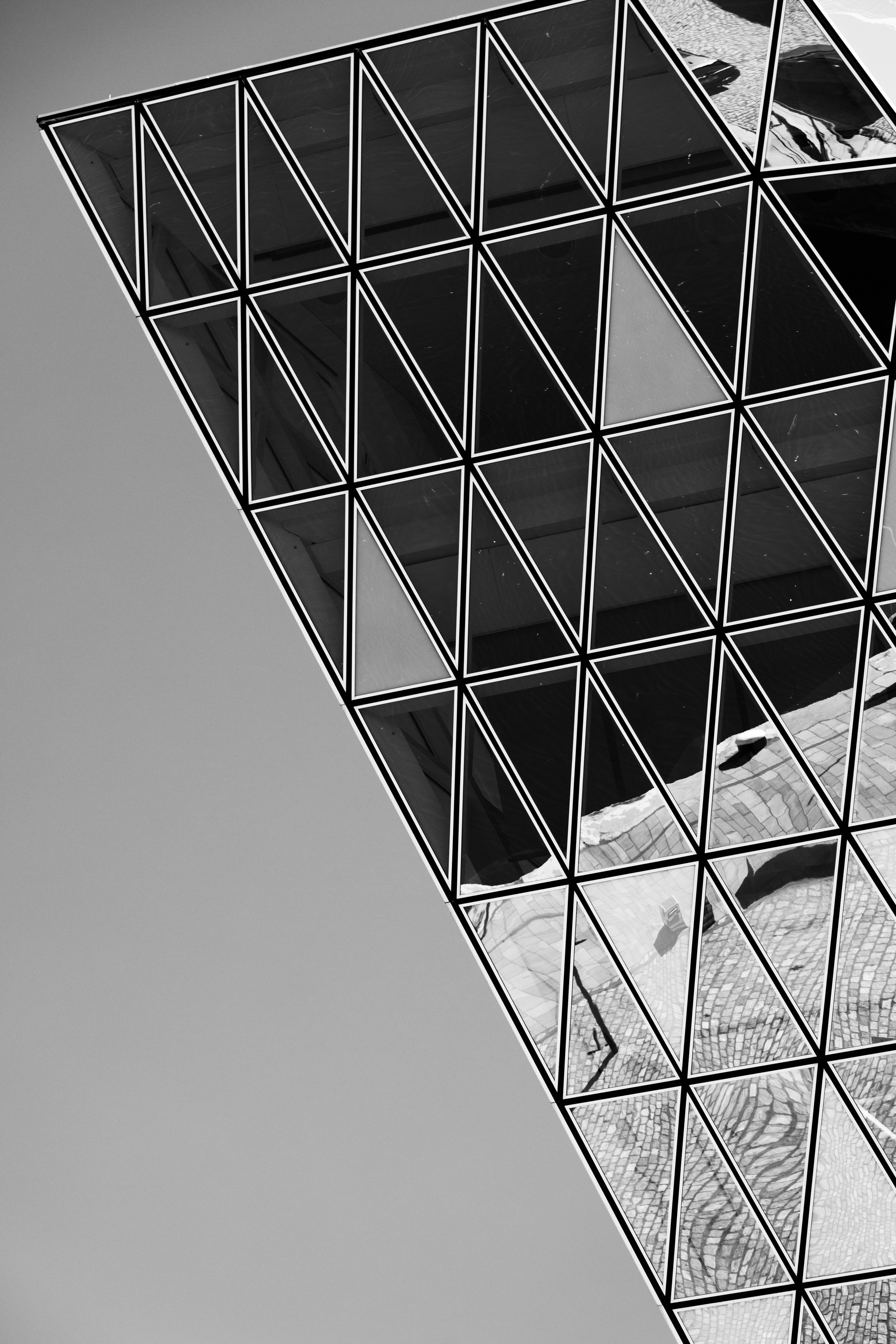 Monochrome high contrast detail shot of the reflections that appear on the glass panels — here one a sharp end point — on the Port House by Zaha Hadid — Antwerp, Belgium