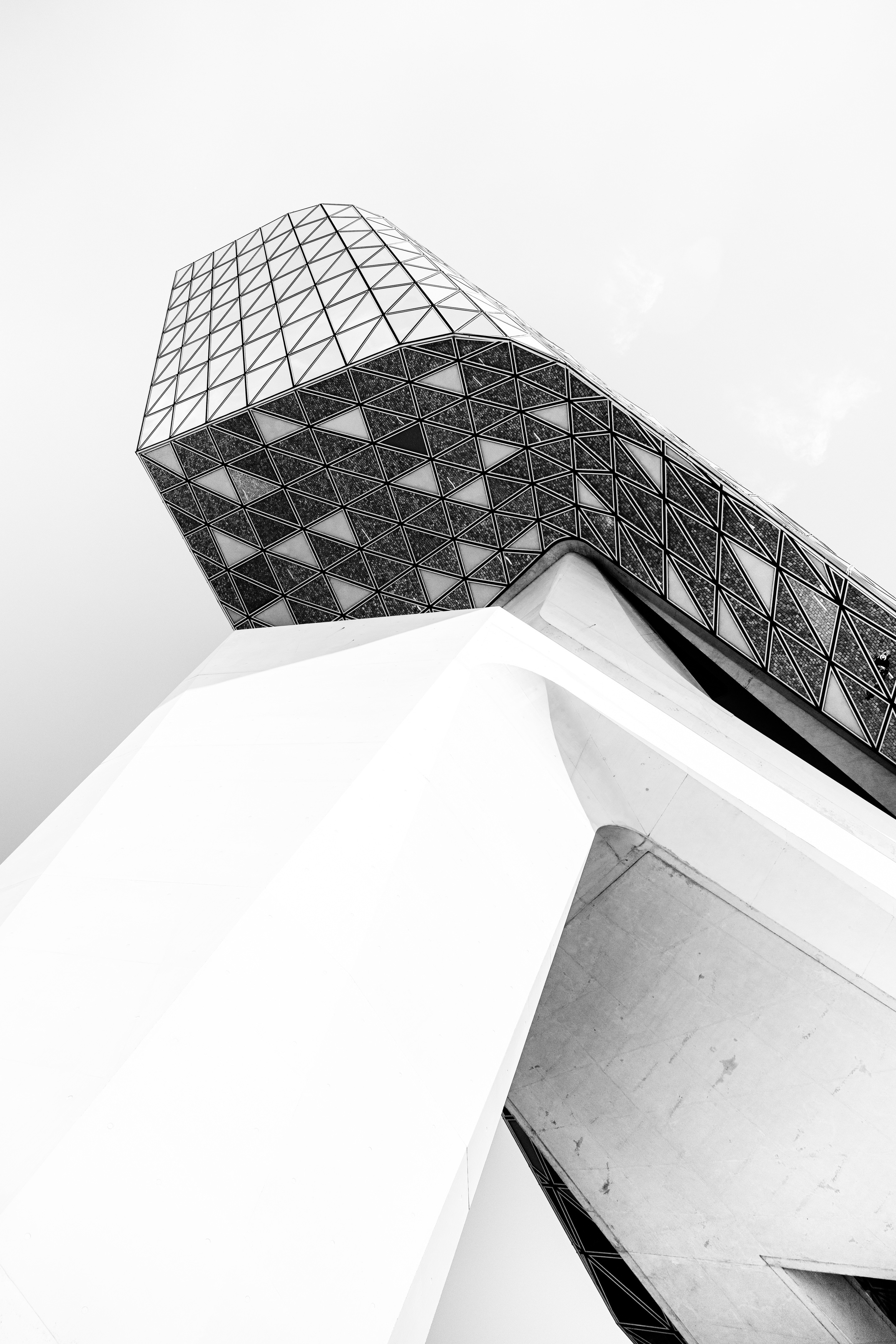 Detail shot of the Port House by Zaha Hadid, showing the underside of the glass extension connected to the huge concrete support column in monochrome — Antwerp, Belgium