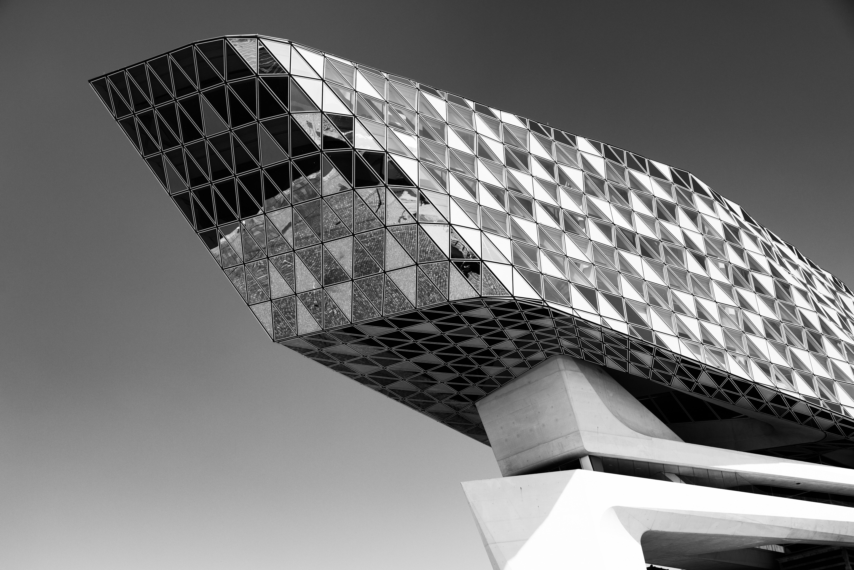 Monochrome high contrast perspective of the glass extension and the top of the concrete support column on the Port House by Zaha Hadid — Antwerp, Belgium