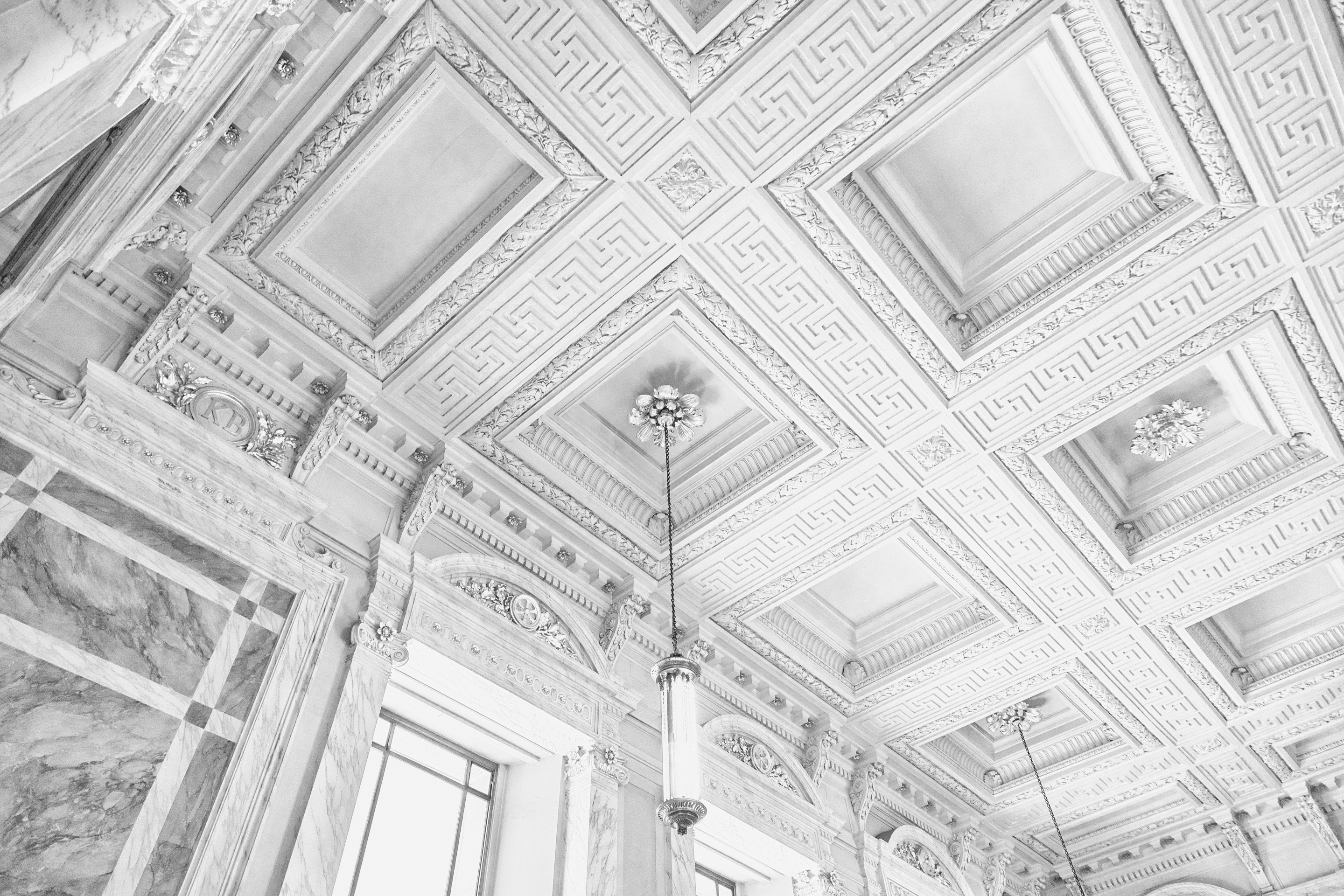 A detail shot of the celling plasterwork in this light and airy black and white photo of the main cafe at Antwerp Central Station — Antwerp, Belgium