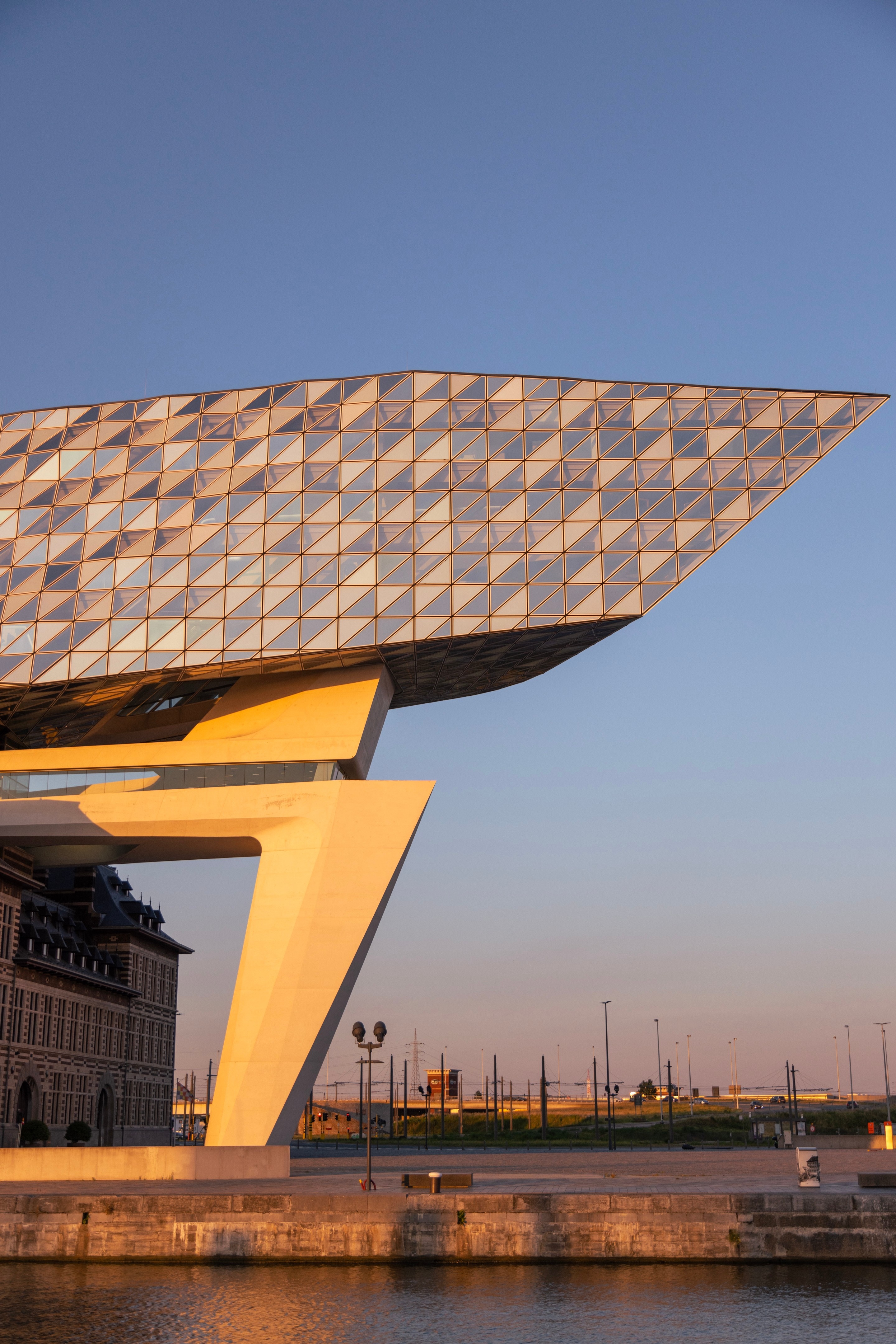 Western elevation of The Port House Zaha Hadid during golden hour, with the glass extension forming a sharp point — Antwerp, Belgium