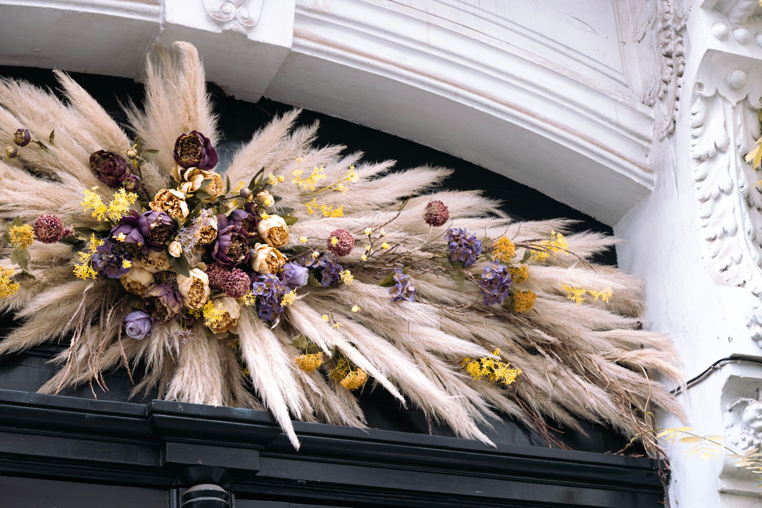 An arrangement of dried flowers decorate the top of a doorway in Antwerp City, Belgium