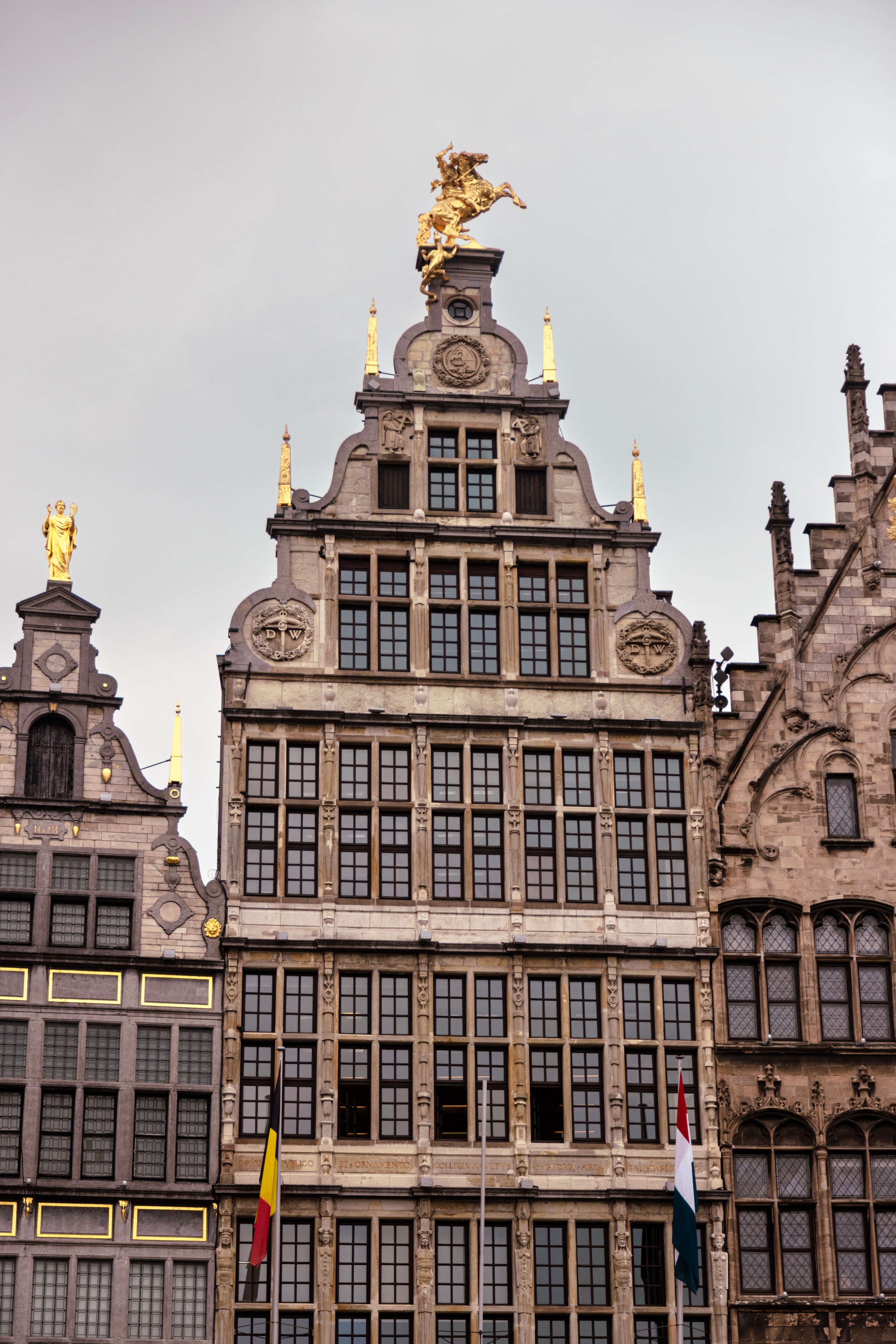 One of the mediaeval mechant storefronts that surround the Market Square. It is decorated with golden statues; obelisks, priests and a large statue of St George slaying the dragon — Antwerp City, Belgium