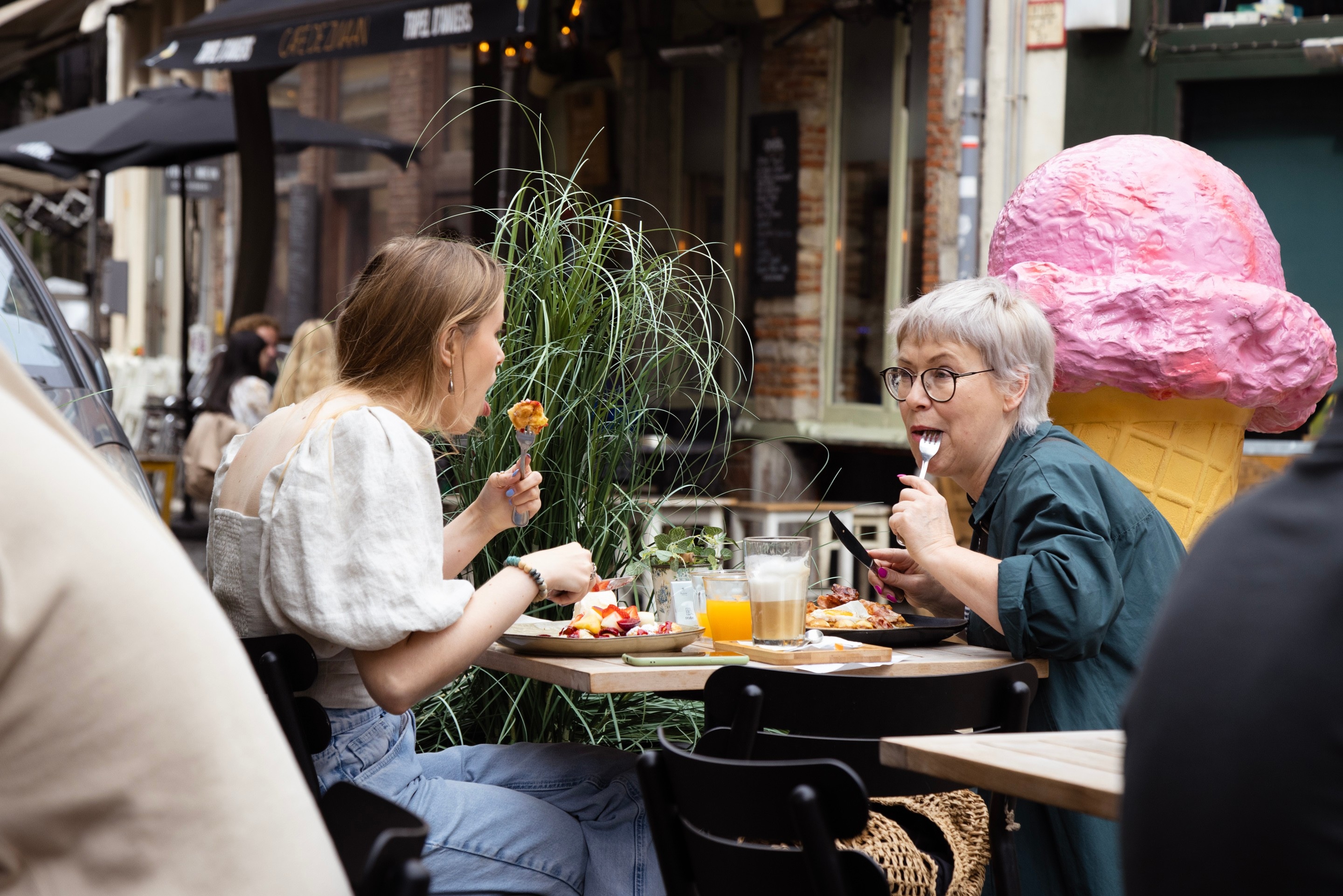 Two woman eat breakfast whilst facing and talking to each other — Antwerp City, Belgium