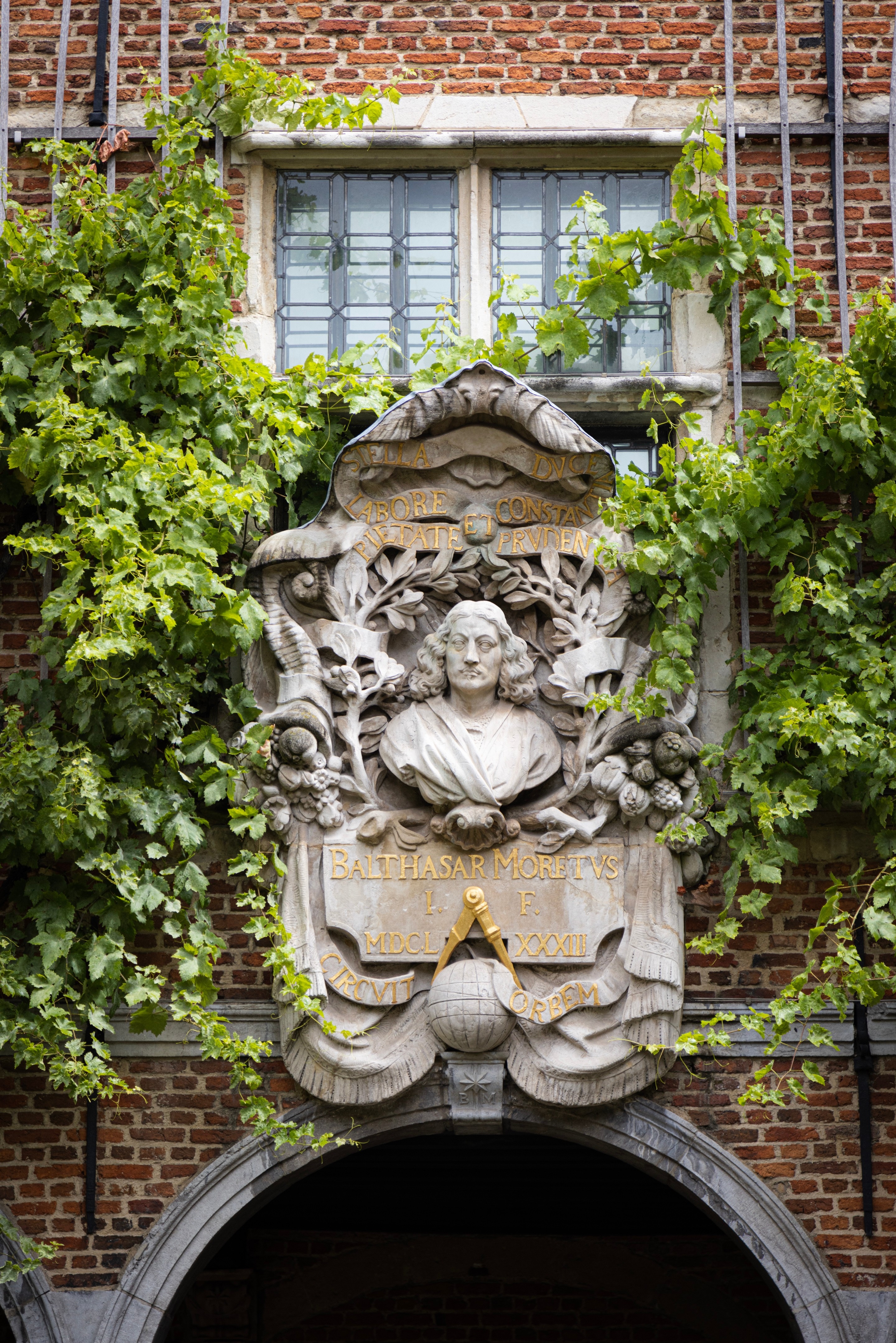 A plaster relief of Balthasar Moretus in an elegant courtyard garden, surrounded by grapevines — Museum Plantin-Moretus, Antwerp, Belgium 