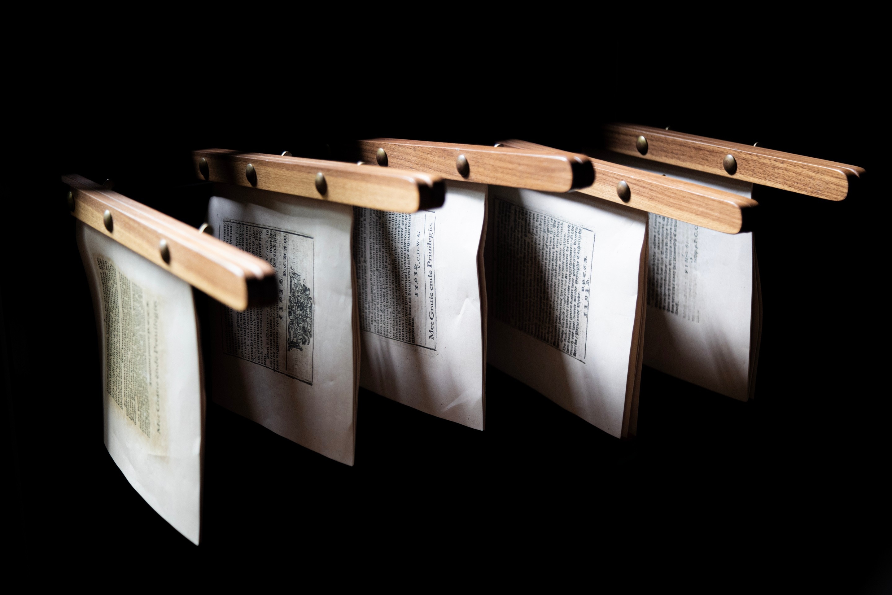 Five examples of the printed output from the Museum Plantin-Moretus, clamped between wood and attached a display stand — Antwerp, Belgium 