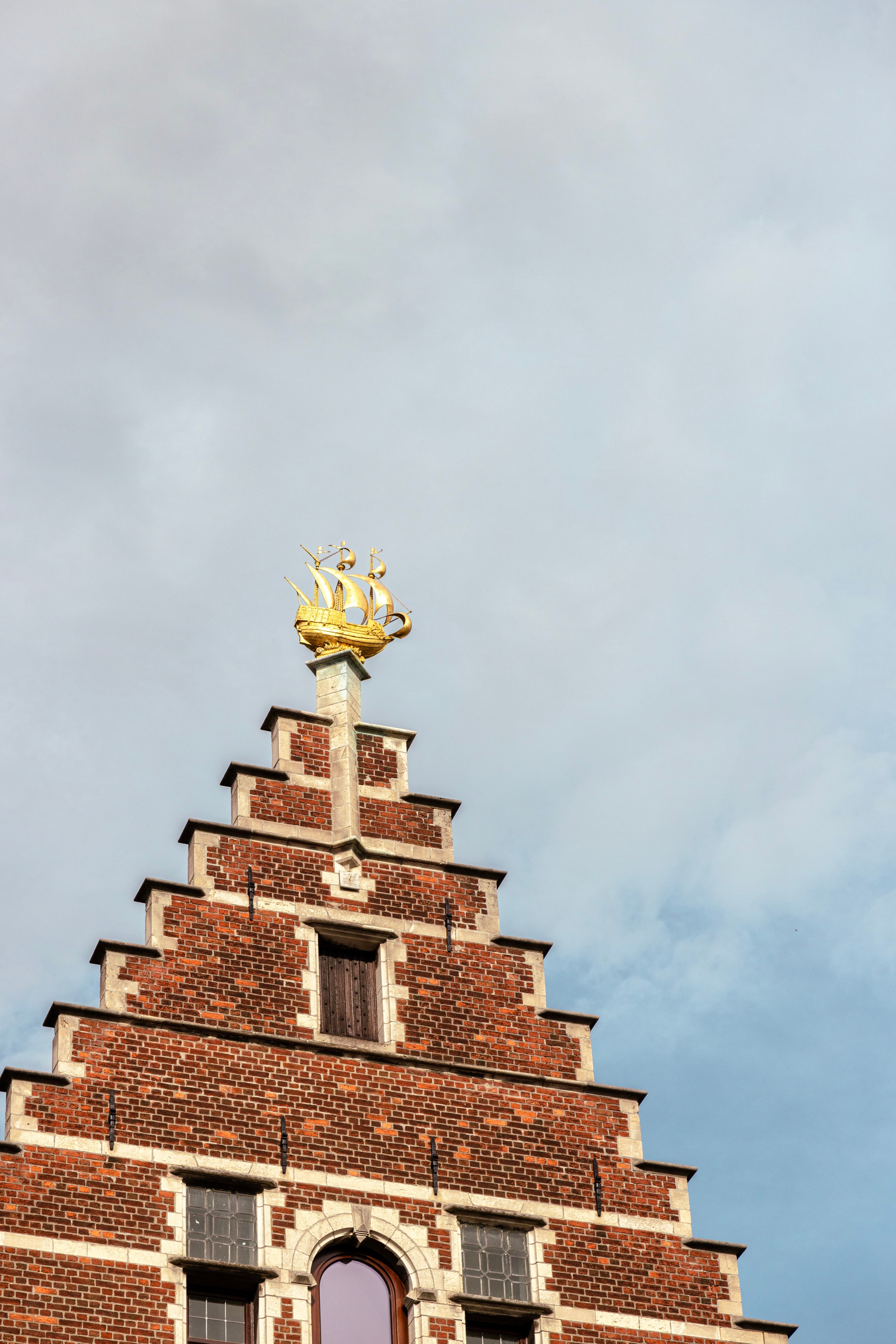 One of the mediaeval mechant storefronts that surround the Market Square. It is decorated on top with a large golden statue of a ship — Main Square, Antwerp City, Belgium