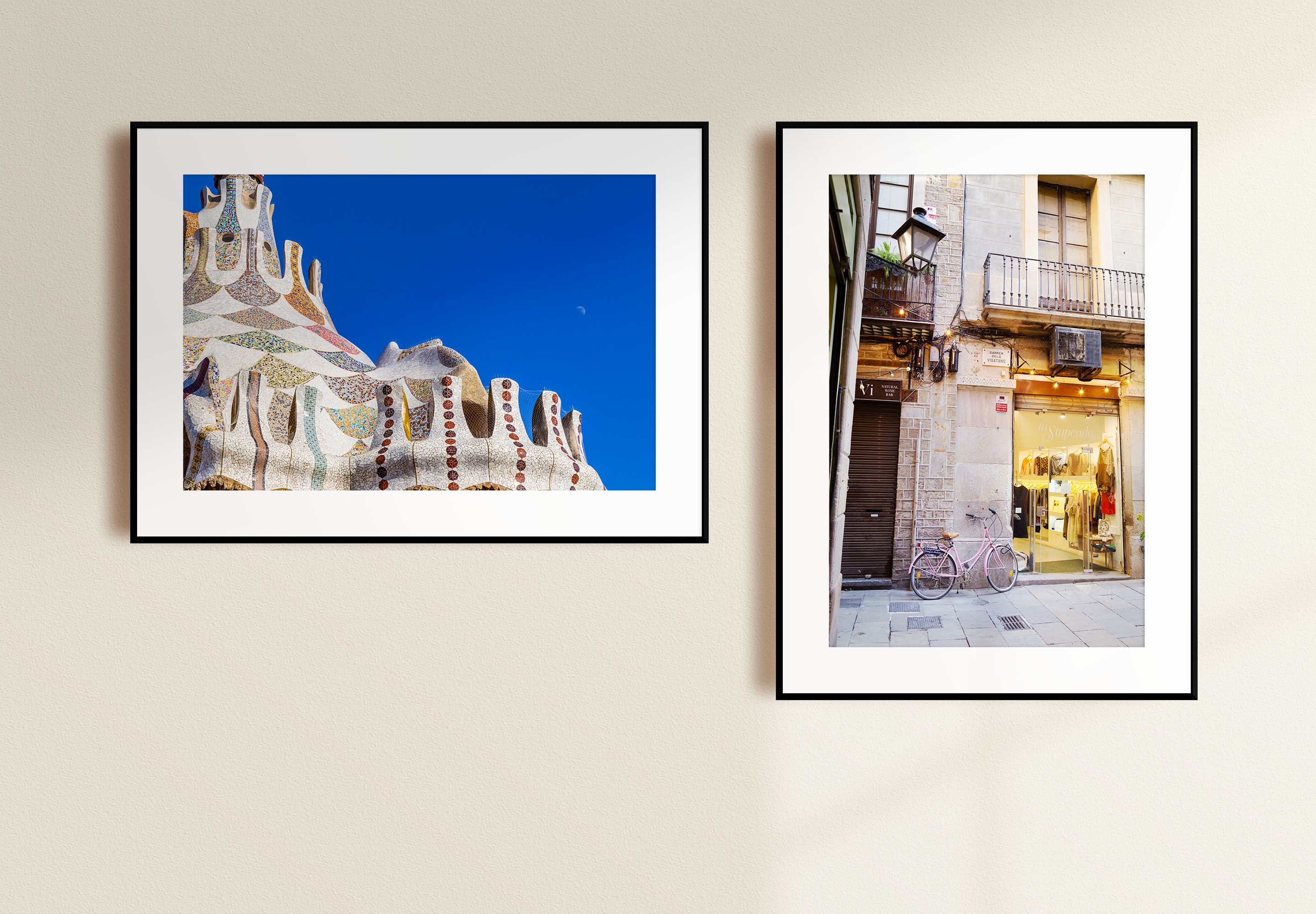 Two mounted fine art photographic prints. Landscape, to the left, showing Gaudí's Gingerbread House set agains a striking blue sky with the daytime moon. Portrait, to the right, showing a pink bicycle resting against a stone wall in an alleyway in El Born district — Barcelona, Spain