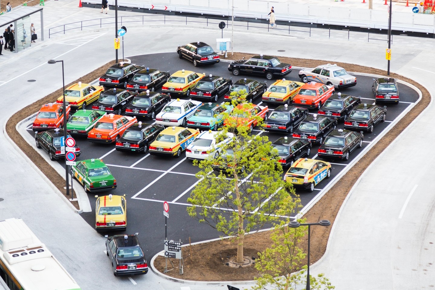 An intriguing taxi rank outside Tokyo Central Station. Pristine taxis patiently queue in grid formation whilst awaiting passengers — Tokyo, Japan